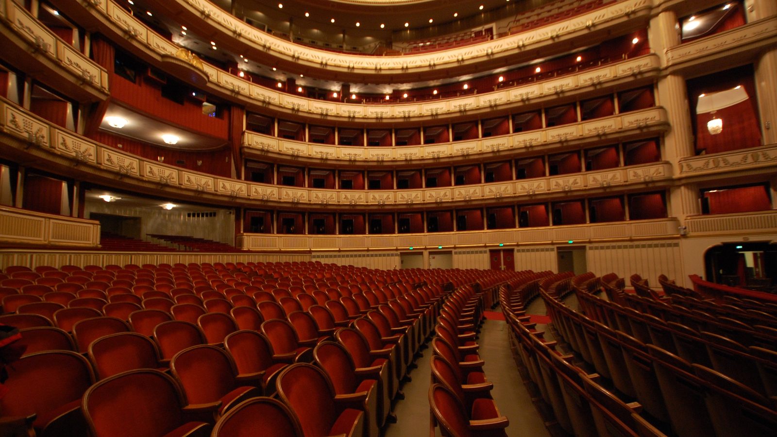 The horseshoe tiers of an opera house seen from the stage