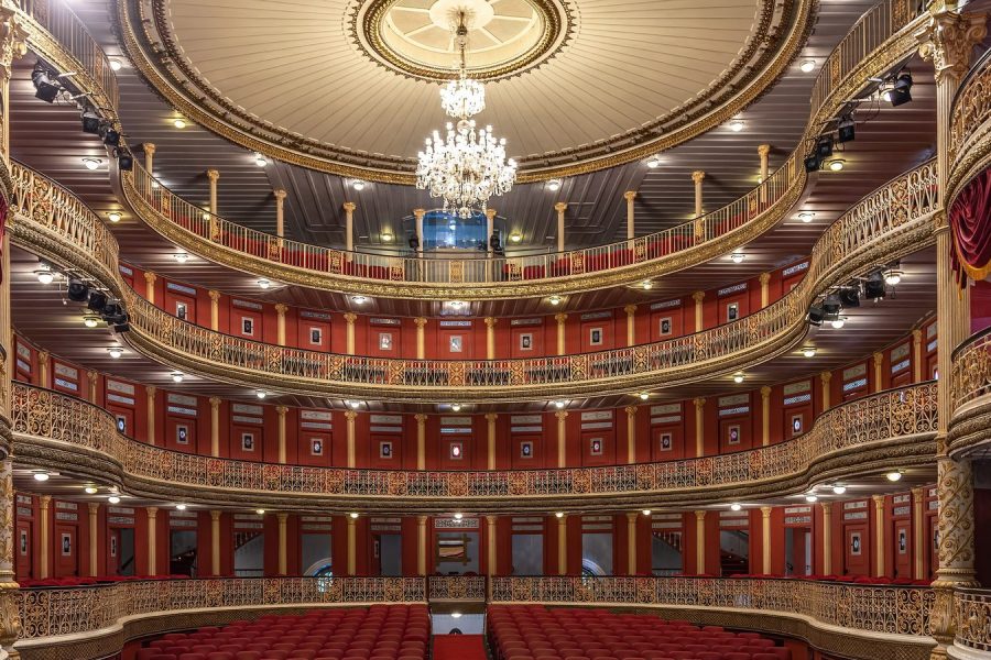 An opera house auditorium, its proscenium arch and orchestra pit in the foreground