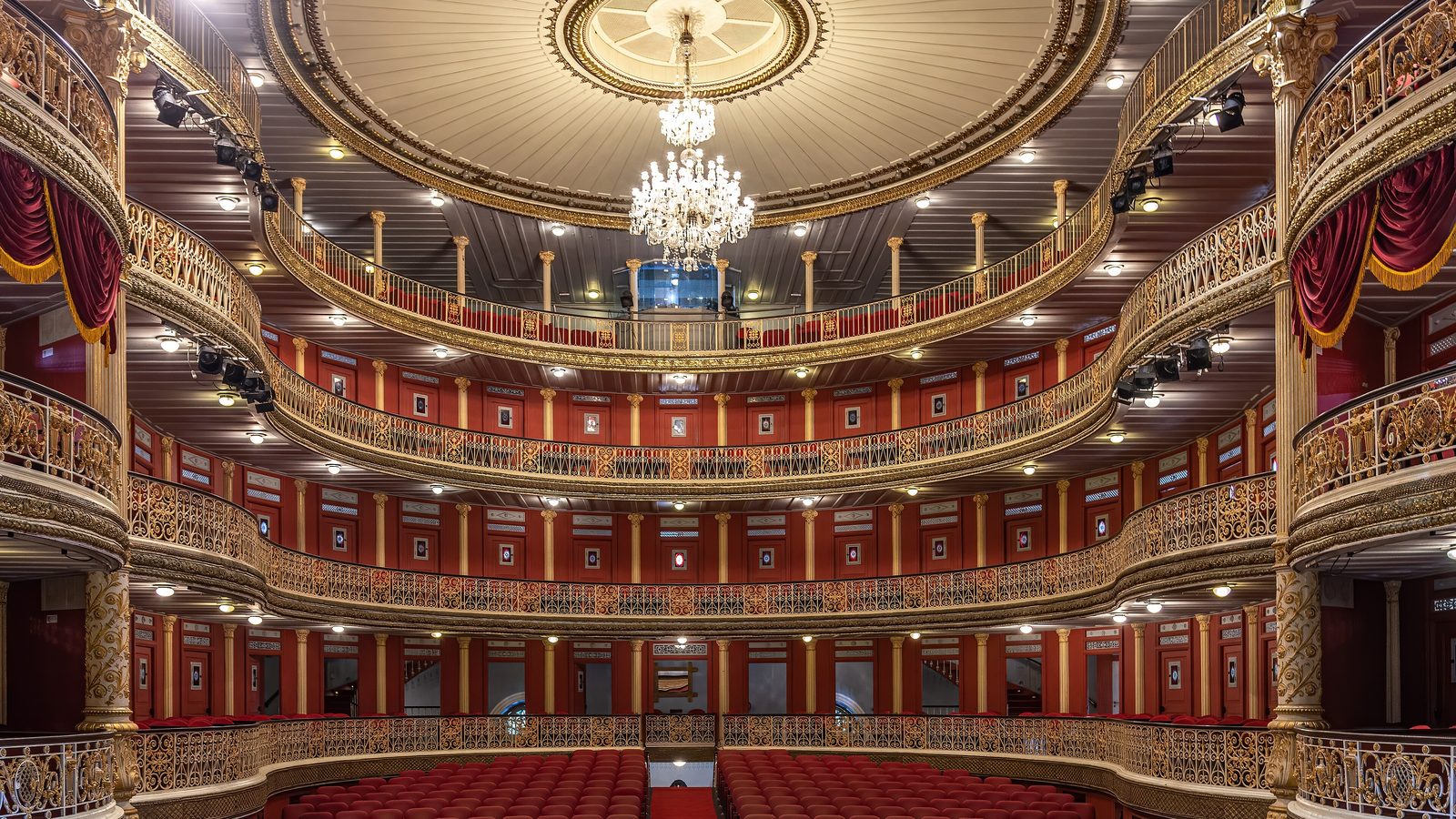 An opera house auditorium, its proscenium arch and orchestra pit in the foreground